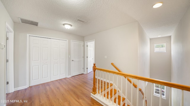 18 Amistad Dr, Saint Augustine, FL 32086 - corridor featuring an upstairs landing, light wood finished floors, a textured ceiling, and baseboards
