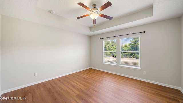 18 Amistad Dr, Saint Augustine, FL 32086 - unfurnished room with a raised ceiling, wood finished floors, baseboards, a ceiling fan, and a textured ceiling