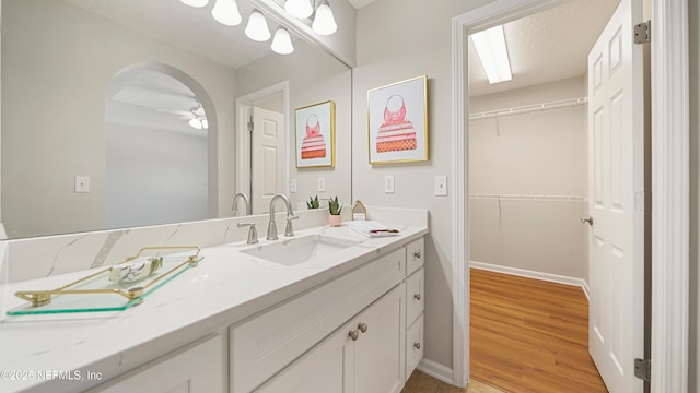 18 Amistad Dr, Saint Augustine, FL 32086 - bathroom with vanity, wood finished floors, baseboards, a ceiling fan, and a walk in closet