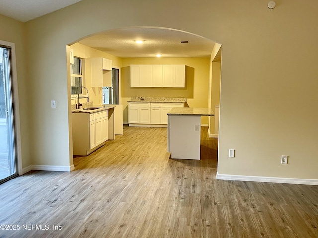 3527 Sheldon Rd, Orange Park, FL 32073 - kitchen featuring a sink, arched walkways, light wood-type flooring, white cabinetry, and baseboards