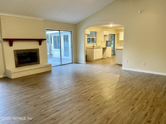 3527 Sheldon Rd, Orange Park, FL 32073 - unfurnished living room with baseboards, light wood-type flooring, a sink, arched walkways, and lofted ceiling