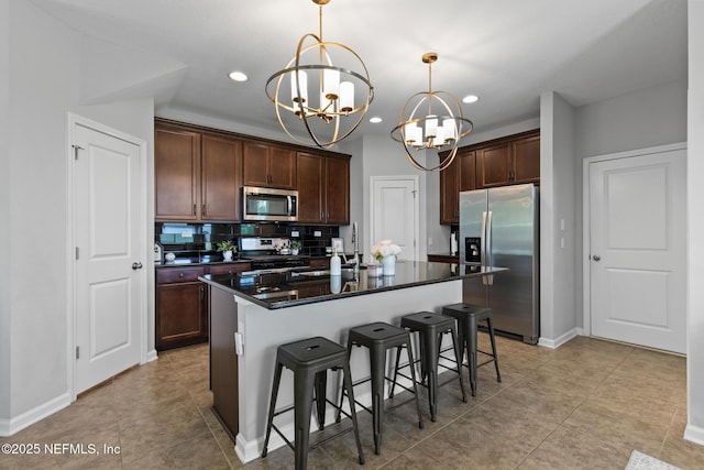 11286 Minnetta Ct, Jacksonville, FL 32256 - kitchen with appliances with stainless steel finishes, a chandelier, dark countertops, a kitchen bar, and decorative backsplash
