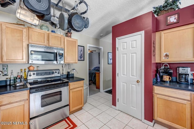 7041 Catlett Rd, Saint Augustine, FL 32095 - kitchen featuring stainless steel appliances, dark countertops, a textured ceiling, light tile patterned floors, and light brown cabinets