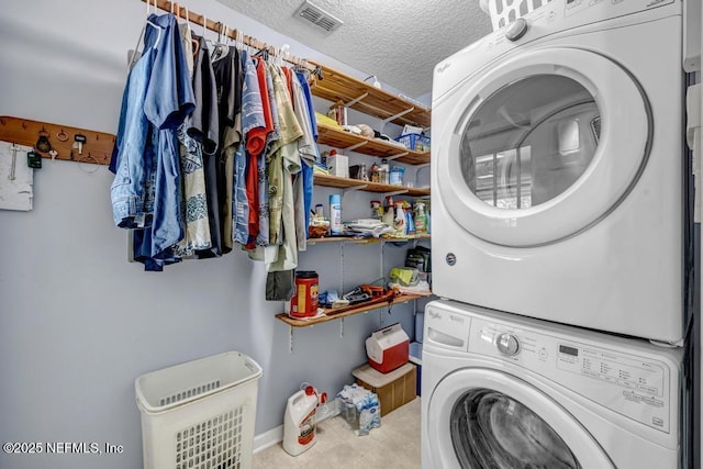 7041 Catlett Rd, Saint Augustine, FL 32095 - laundry area featuring stacked washing machine and dryer, tile patterned floors, a textured ceiling, and baseboards