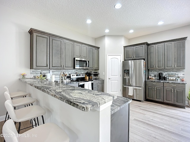 9413 Alma St, Jacksonville, FL 32220 - kitchen with appliances with stainless steel finishes, a kitchen breakfast bar, a sink, decorative backsplash, and a textured ceiling