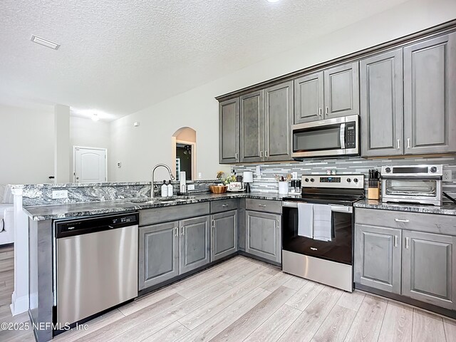 9413 Alma St, Jacksonville, FL 32220 - kitchen with stainless steel appliances, a sink, arched walkways, a peninsula, and light wood finished floors