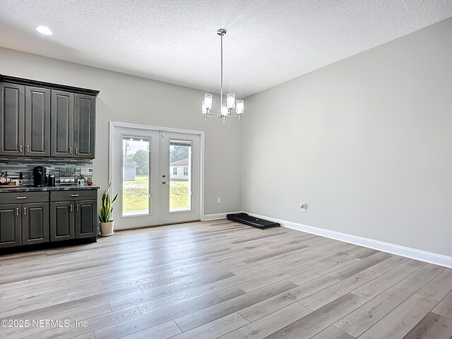 9413 Alma St, Jacksonville, FL 32220 - unfurnished dining area with french doors, a chandelier, light wood-style floors, a textured ceiling, and baseboards