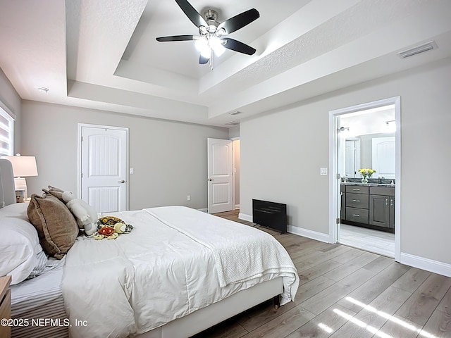 9413 Alma St, Jacksonville, FL 32220 - bedroom with a raised ceiling, light wood-style flooring, baseboards, connected bathroom, and a ceiling fan