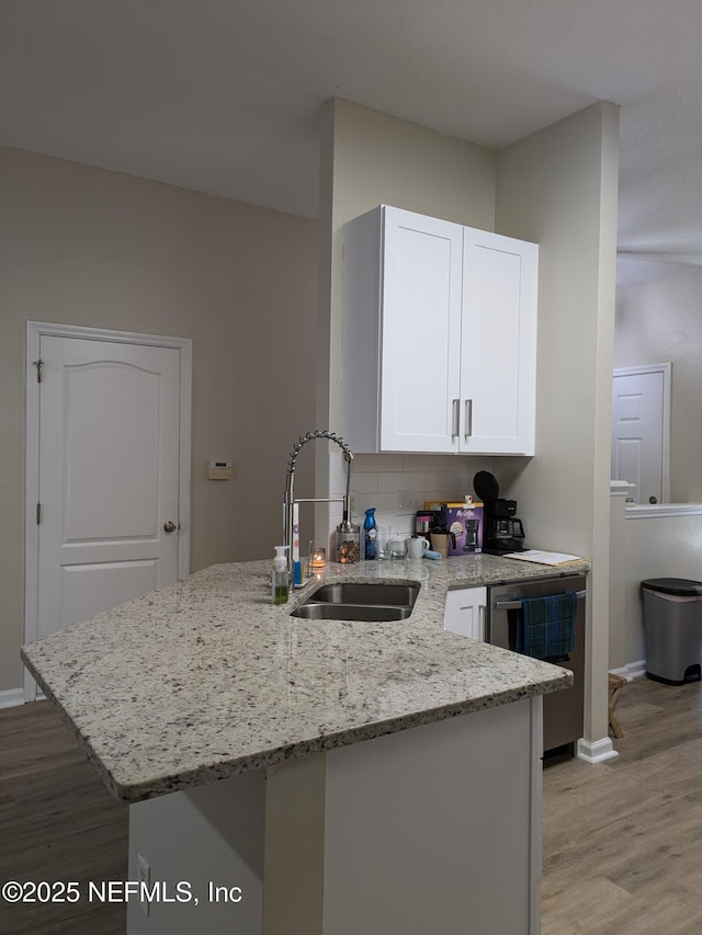 12429 Pecan Hickory Ct, Jacksonville, FL 32226 - kitchen with a sink, stainless steel dishwasher, light wood-type flooring, white cabinets, and light stone counters