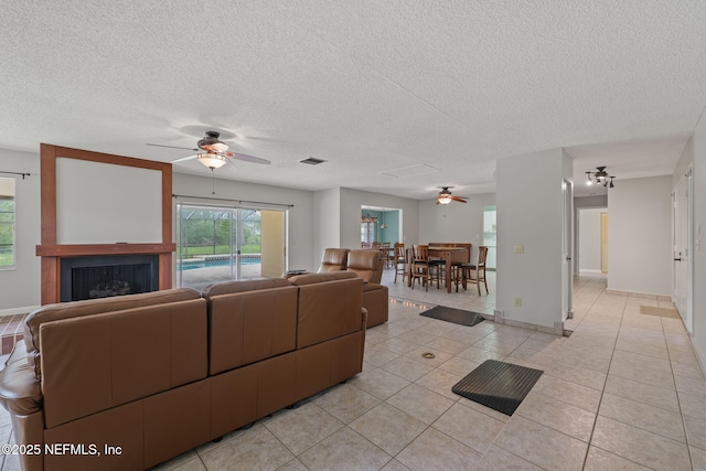 419 Sevilla Dr, Saint Augustine, FL 32086 - living area featuring a ceiling fan, light tile patterned floors, a textured ceiling, a fireplace, and baseboards