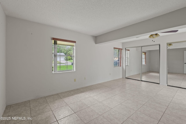 419 Sevilla Dr, Saint Augustine, FL 32086 - unfurnished bedroom with multiple closets, a textured ceiling, light tile patterned flooring, and a ceiling fan