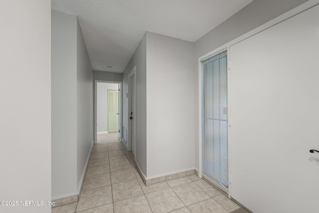419 Sevilla Dr, Saint Augustine, FL 32086 - corridor featuring baseboards, light tile patterned flooring, and a textured ceiling