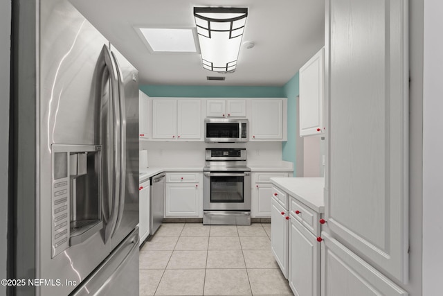 419 Sevilla Dr, Saint Augustine, FL 32086 - kitchen featuring appliances with stainless steel finishes, light countertops, light tile patterned floors, and white cabinets