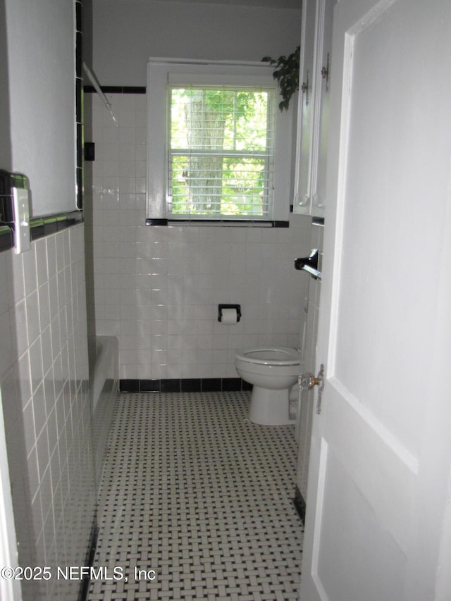 870 Allison St, Jacksonville, FL 32254 - full bath featuring tile walls, toilet, shower / tub combination, and a wainscoted wall