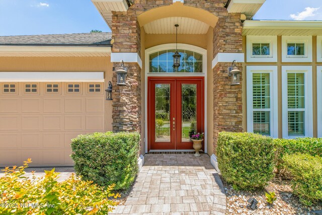 117 Pineta Way, Saint Johns, FL 32259 - entrance to property with stone siding, french doors, an attached garage, and roof with shingles