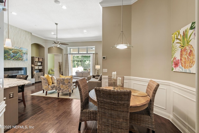 117 Pineta Way, Saint Johns, FL 32259 - dining space with a ceiling fan, ornamental molding, a glass covered fireplace, a wainscoted wall, and dark wood-type flooring