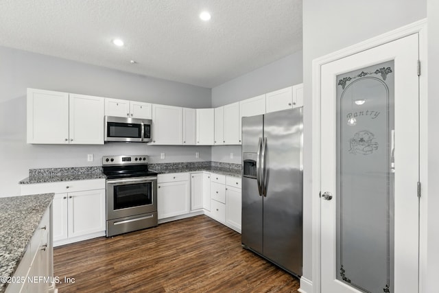 9706 Sibbald Rd, Jacksonville, FL 32219 - kitchen featuring stainless steel appliances, a textured ceiling, stone countertops, white cabinetry, and dark wood finished floors
