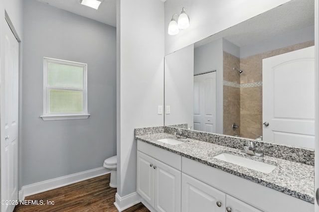 9706 Sibbald Rd, Jacksonville, FL 32219 - bathroom featuring double vanity, toilet, baseboards, tiled shower, and wood finished floors