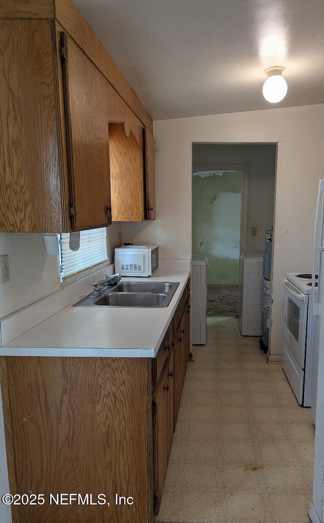 4649 Fairleigh Ave, Jacksonville, FL 32208 - kitchen featuring white appliances, a sink, light floors, washer / clothes dryer, and brown cabinets