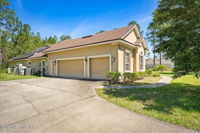 9955 Kings Crossing Dr E, Jacksonville, FL 32219 - view of home's exterior with an attached garage, solar panels, a yard, concrete driveway, and stucco siding