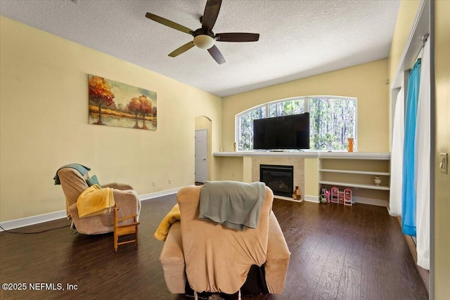 9955 Kings Crossing Dr E, Jacksonville, FL 32219 - living room with a textured ceiling, a ceiling fan, wood-type flooring, a tile fireplace, and arched walkways