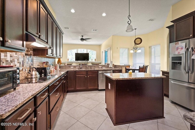 9955 Kings Crossing Dr E, Jacksonville, FL 32219 - kitchen with appliances with stainless steel finishes, a sink, under cabinet range hood, light stone counters, and decorative backsplash