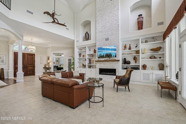 2579 Woodgrove Rd, Fleming Island, FL 32003 - living area with a towering ceiling, built in shelves, ornate columns, light tile patterned flooring, and a large fireplace
