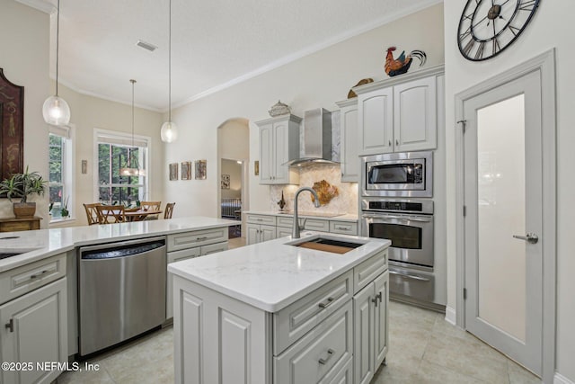 2579 Woodgrove Rd, Fleming Island, FL 32003 - kitchen with stainless steel appliances, wall chimney range hood, backsplash, an island with sink, and arched walkways