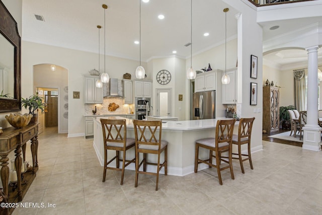2579 Woodgrove Rd, Fleming Island, FL 32003 - kitchen featuring wall chimney exhaust hood, appliances with stainless steel finishes, arched walkways, crown molding, and ornate columns