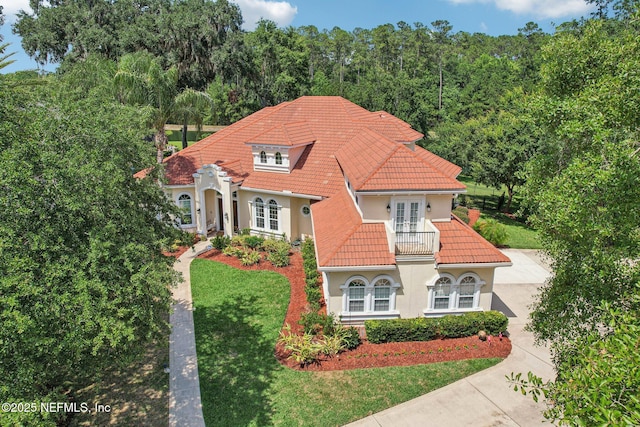 2579 Woodgrove Rd, Fleming Island, FL 32003 - mediterranean / spanish house with french doors, a balcony, a tile roof, concrete driveway, and stucco siding