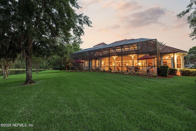 2579 Woodgrove Rd, Fleming Island, FL 32003 - back of house at dusk featuring a lawn and a lanai