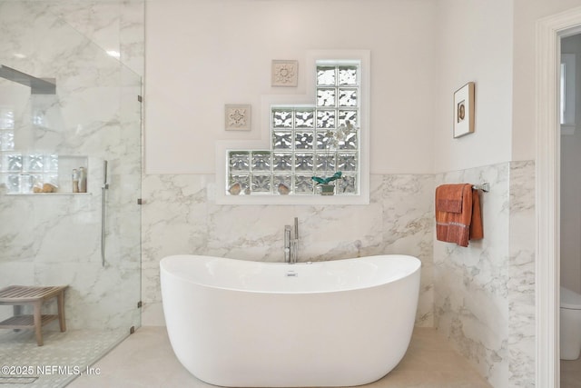 2579 Woodgrove Rd, Fleming Island, FL 32003 - full bathroom with tile walls, a freestanding tub, a marble finish shower, and a wainscoted wall