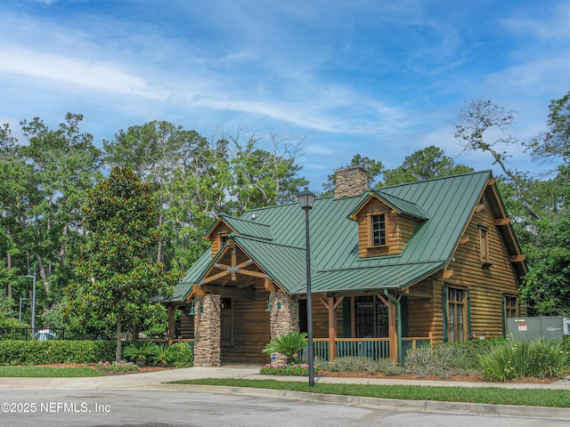 2579 Woodgrove Rd, Fleming Island, FL 32003 - cabin featuring a standing seam roof, a porch, a chimney, metal roof, and stone siding