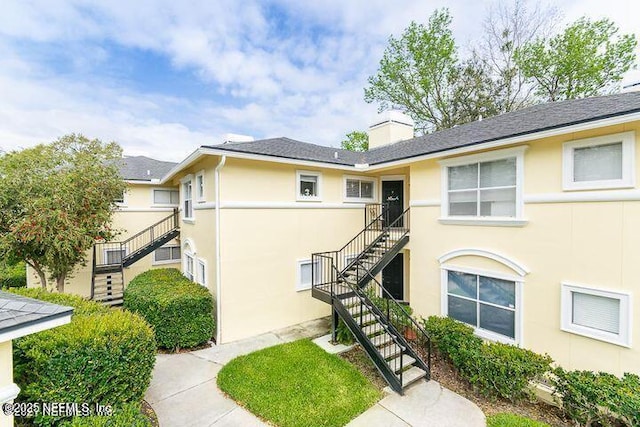 1800 The Greens Way Unit 406, Jacksonville Beach, FL 32250 - view of front of property featuring stairway, stucco siding, and a chimney