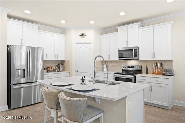2629 Cold Stream Ln, Green Cove Springs, FL 32043 - kitchen with appliances with stainless steel finishes, light wood-style floors, white cabinetry, a kitchen island with sink, and crown molding