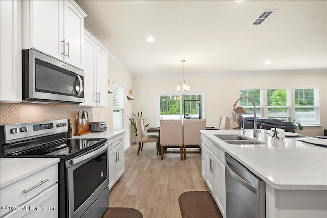2629 Cold Stream Ln, Green Cove Springs, FL 32043 - kitchen featuring stainless steel appliances, a chandelier, ornamental molding, white cabinetry, and light wood-type flooring