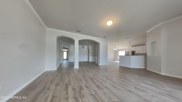 4053 Trail Ridge Rd, Middleburg, FL 32068 - unfurnished living room with crown molding, baseboards, light wood finished floors, and arched walkways