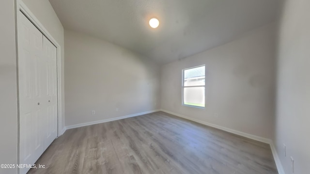 4053 Trail Ridge Rd, Middleburg, FL 32068 - unfurnished bedroom featuring a closet, baseboards, vaulted ceiling, and light wood-style floors