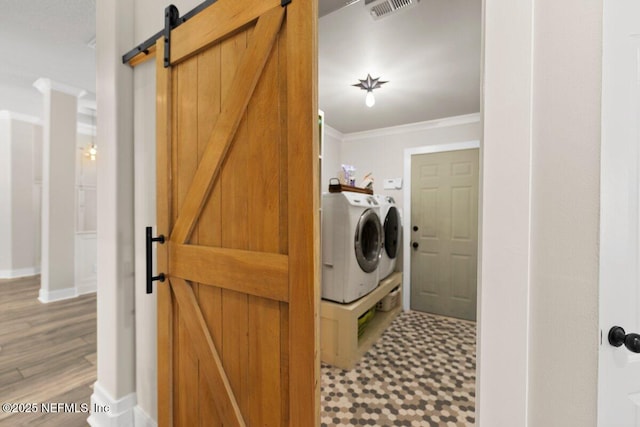 1759 Rising Oaks Dr, Jacksonville, FL 32223 - washroom featuring a barn door, washer and dryer, tile patterned floors, crown molding, and baseboards