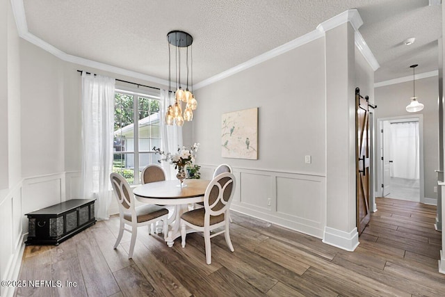 1759 Rising Oaks Dr, Jacksonville, FL 32223 - dining space with a barn door, a decorative wall, wood finished floors, a textured ceiling, and wainscoting
