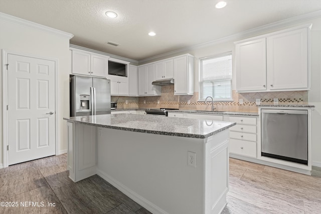 109 Sweet Pine Trl, Ponte Vedra, FL 32081 - kitchen with appliances with stainless steel finishes, under cabinet range hood, a sink, a kitchen island, and white cabinets