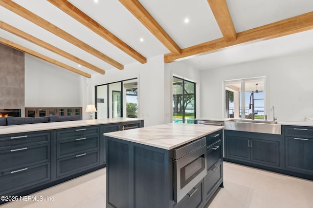 95544 Wilder Blvd, Fernandina Beach, FL 32034 - kitchen featuring stainless steel microwave, a sink, light tile patterned floors, a kitchen island, and open floor plan
