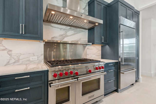 95544 Wilder Blvd, Fernandina Beach, FL 32034 - kitchen with wall chimney exhaust hood, high quality appliances, backsplash, and blue cabinets