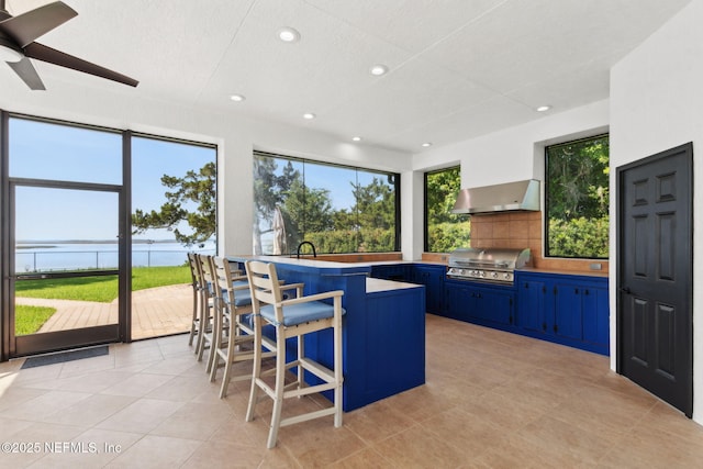 95544 Wilder Blvd, Fernandina Beach, FL 32034 - kitchen featuring blue cabinets, wall chimney exhaust hood, recessed lighting, decorative backsplash, and ceiling fan