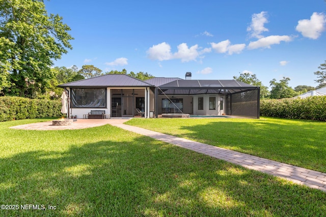 95544 Wilder Blvd, Fernandina Beach, FL 32034 - rear view of house featuring an outdoor fire pit, a yard, a patio area, a chimney, and glass enclosure
