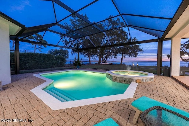 95544 Wilder Blvd, Fernandina Beach, FL 32034 - pool at dusk featuring a pool with connected hot tub, a patio area, a water view, and glass enclosure
