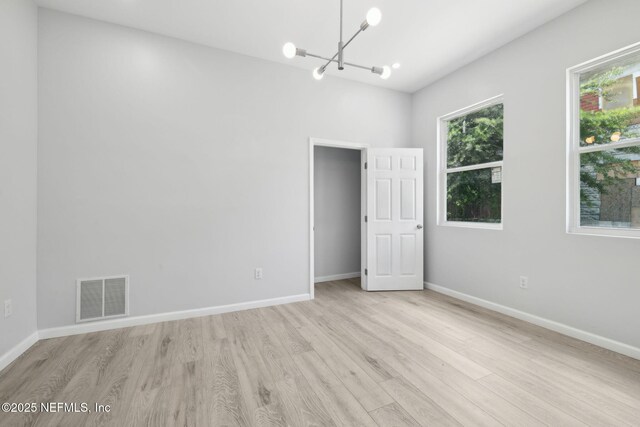 2010 N Main St, Jacksonville, FL 32206 - spare room featuring a chandelier, light wood-style flooring, and baseboards