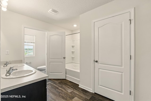 3238 Little Fawn Ln, Green Cove Springs, FL 32137 - bathroom featuring double vanity, wood finished floors, a textured ceiling, toilet, and washtub / shower combination