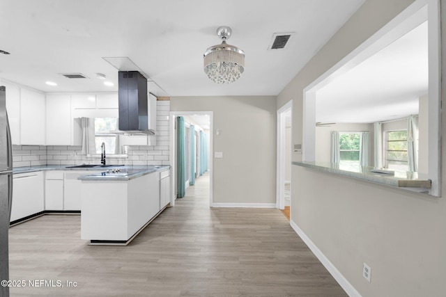 7930 Bellemeade Blvd, Jacksonville, FL 32211 - kitchen featuring wall chimney exhaust hood, white cabinets, backsplash, light countertops, and light wood finished floors