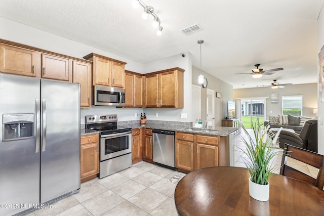 236 Servia Dr, Saint Johns, FL 32259 - kitchen with stainless steel appliances, open floor plan, brown cabinets, ceiling fan, and light tile patterned floors